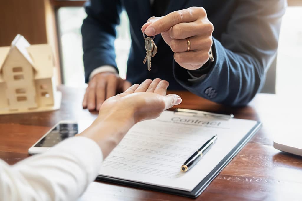 one person handing another a set of keys to represent a buyer buying a home in a seller's market